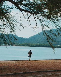 Woman standing by lake against sky