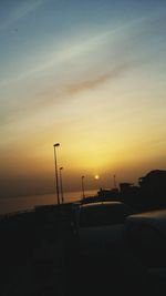 Silhouette car on street against sky during sunset