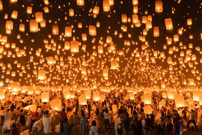 Group of people with illuminated lanterns at night