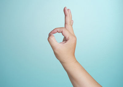 Close-up of human hand gesturing against blue background