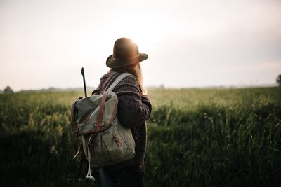 Rear view of woman standing on field against sky