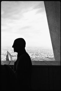 Silhouette man sitting on beach against sky