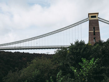 Low angle view of suspension bridge against cloudy sky