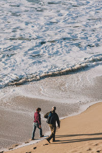 High angle view of friends walking on beach