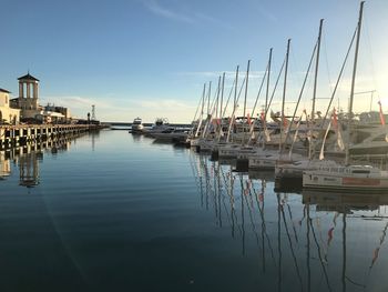 Boats moored in harbor at sunset