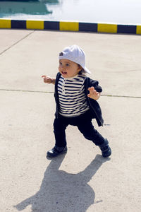 Little boy in a cap standing on the street in the seaport