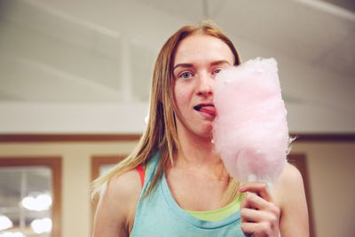 Portrait of young woman licking cotton candy at restaurant