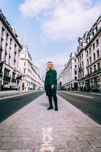 Full length of woman standing on sidewalk in city