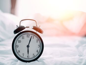 Close-up of alarm clock on bed at home