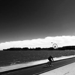 Man riding bicycle on road against sky