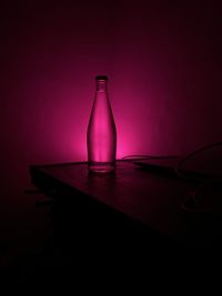 Close-up of glass bottle on table against wall