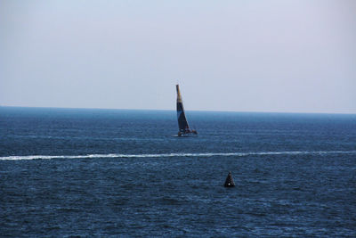 Sailboat in sea against clear sky