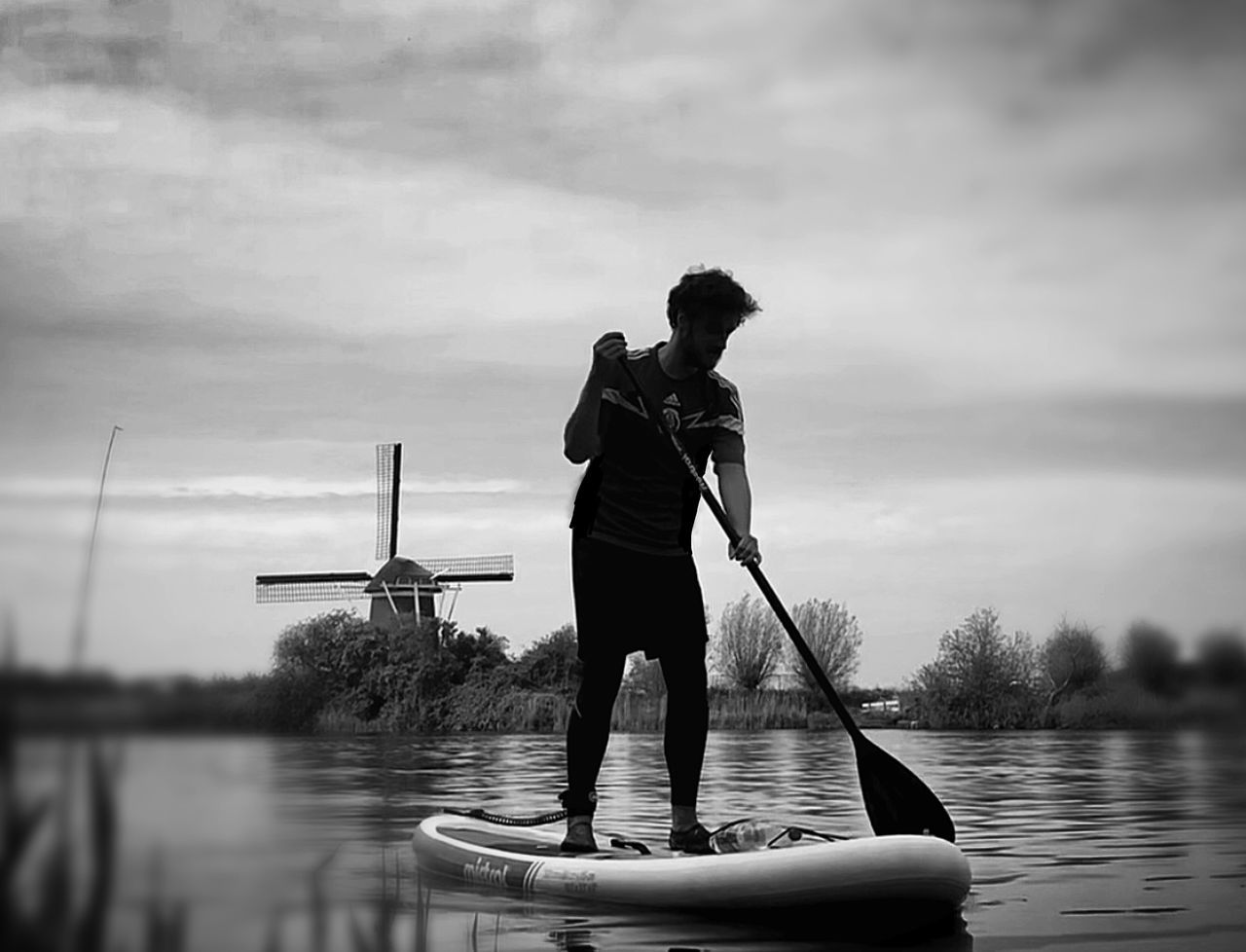 REAR VIEW OF MAN ON BOAT IN LAKE