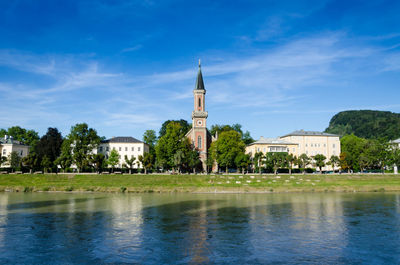 View of lake by building against blue sky