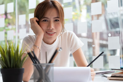 Portrait of smiling woman using phone on table