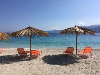 Chairs on beach by sea against sky