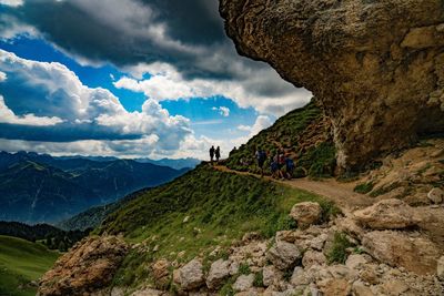 People on rocks against mountains