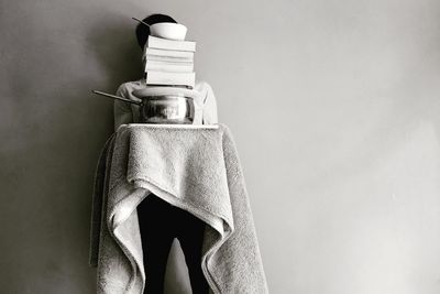 Person carrying objects while standing against gray background