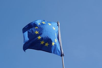 Low angle view of european union flag against clear blue sky during sunny day