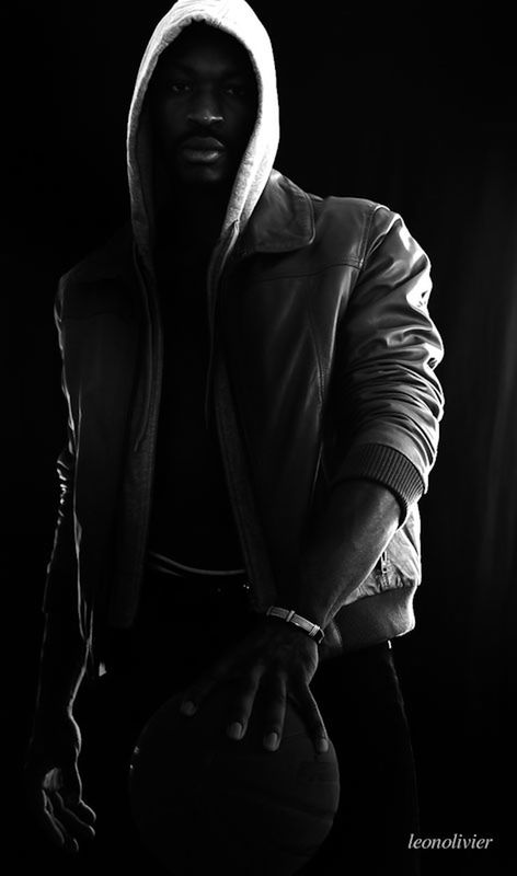 one person, front view, indoors, adult, black background, studio shot, men, three quarter length, clothing, standing, dark, holding, business, portrait, males, suit, serious, young adult, hood, obscured face, contemplation