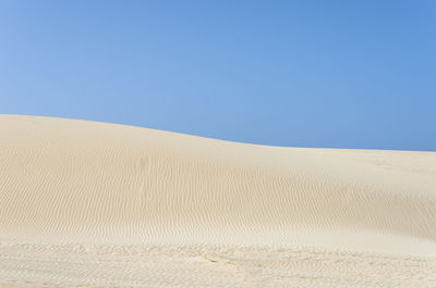 Scenic view of desert against clear blue sky