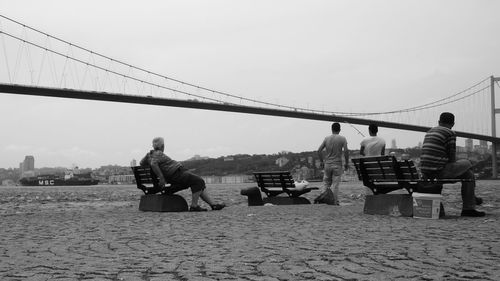 People sitting on bridge against sky