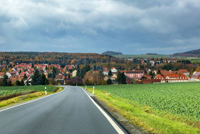 Road amidst green landscape against sky