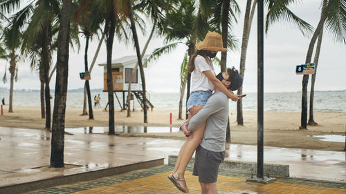 Two people standing by palm trees on the beach with a moment of happiness.