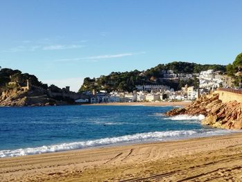 Scenic view of sea by buildings against blue sky