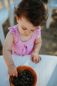 Baby girl picking blackberry from bowl