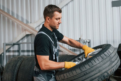 Broken wheel. man in uniform is working in the auto service.