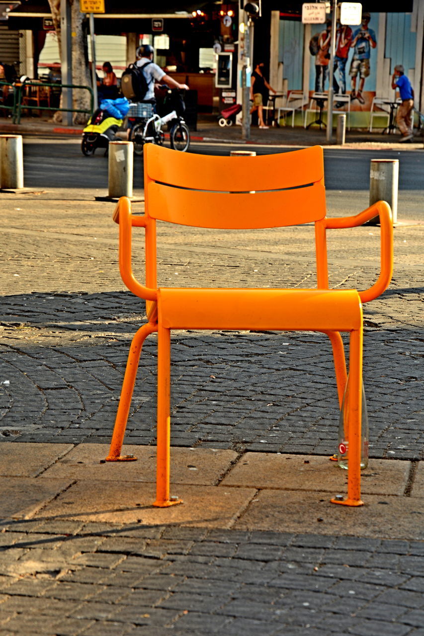 PEOPLE SITTING ON BENCH AT SIDEWALK CAFE BY STREET