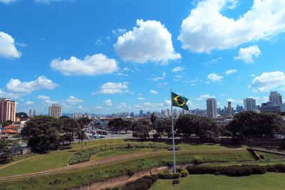 Trees and buildings in city against sky