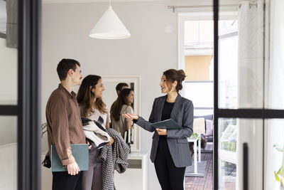 Saleswoman talking with happy male and female clients during house visit