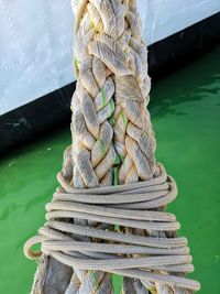 Stack of rope tied to wooden post in lake