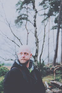 Portrait of man standing by tree against sky