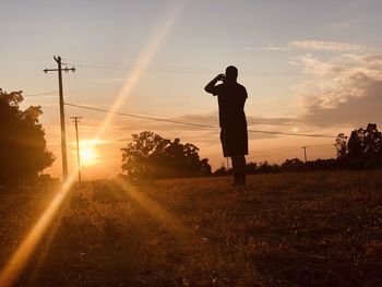 Man photographing sunset on field against sky