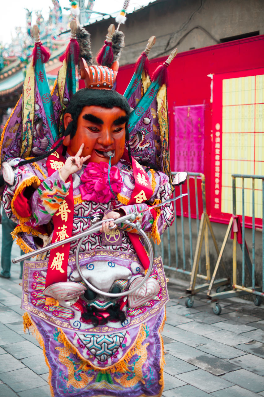 one person, lifestyles, real people, standing, traditional clothing, front view, young adult, art and craft, multi colored, religion, architecture, day, belief, dancing, clothing, spirituality, creativity, outdoors