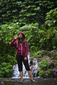 Full length of young woman standing against plants