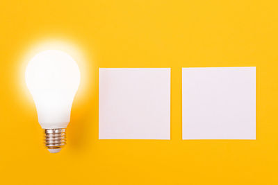 Close-up of illuminated light bulb against yellow wall