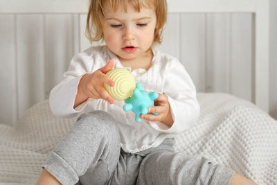 Baby girl playing tactile knobby balls. young child hand plays sensory massage ball