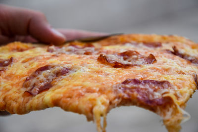 Close-up of hand holding pizza