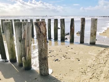 Wooden posts on beach against sky