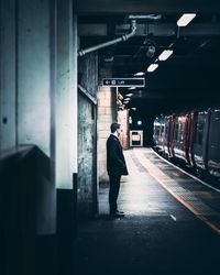 Rear view of man standing at railroad station