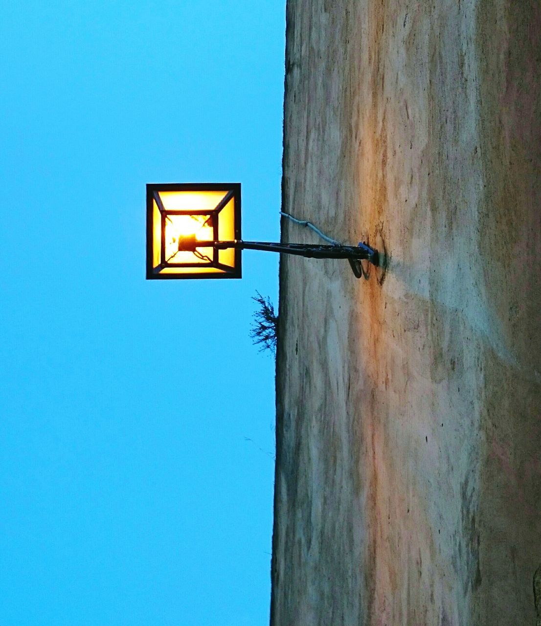 blue, low angle view, clear sky, copy space, built structure, architecture, wall - building feature, lighting equipment, wall, yellow, building exterior, no people, wood - material, sunlight, day, close-up, outdoors, street light, window, protection