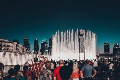 Group of people in city against clear sky