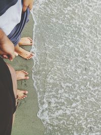 Low section of people standing on sea shore