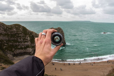 Midsection of man photographing sea against sky