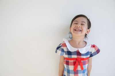 Portrait of smiling girl standing against white background