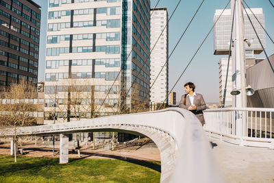 Businessman standing on footbridge against building